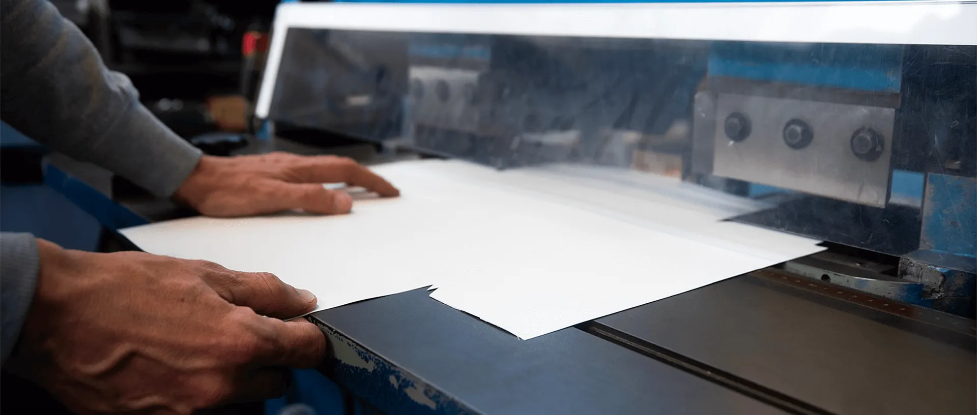 Hands feeding board into a machine in the workshop